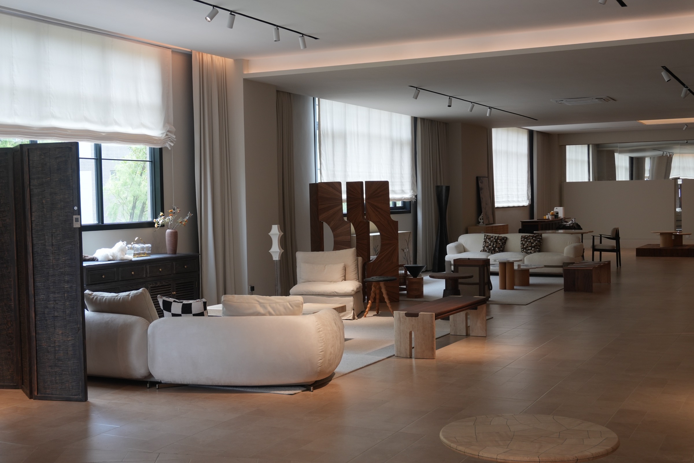 Sculptural white sofas, timber screens and stone tables in a sunlit interior